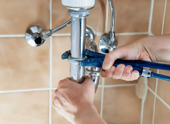 Dos fontaneros trabajando en la instalación de un lavabo, mientras revisan información en una tableta